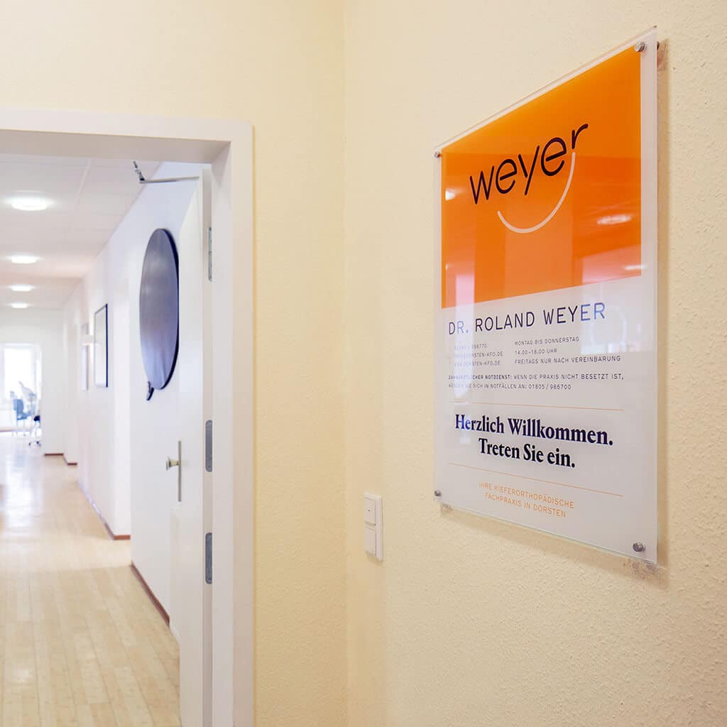 Eingangsbereich der Praxis mit Firmenschild.